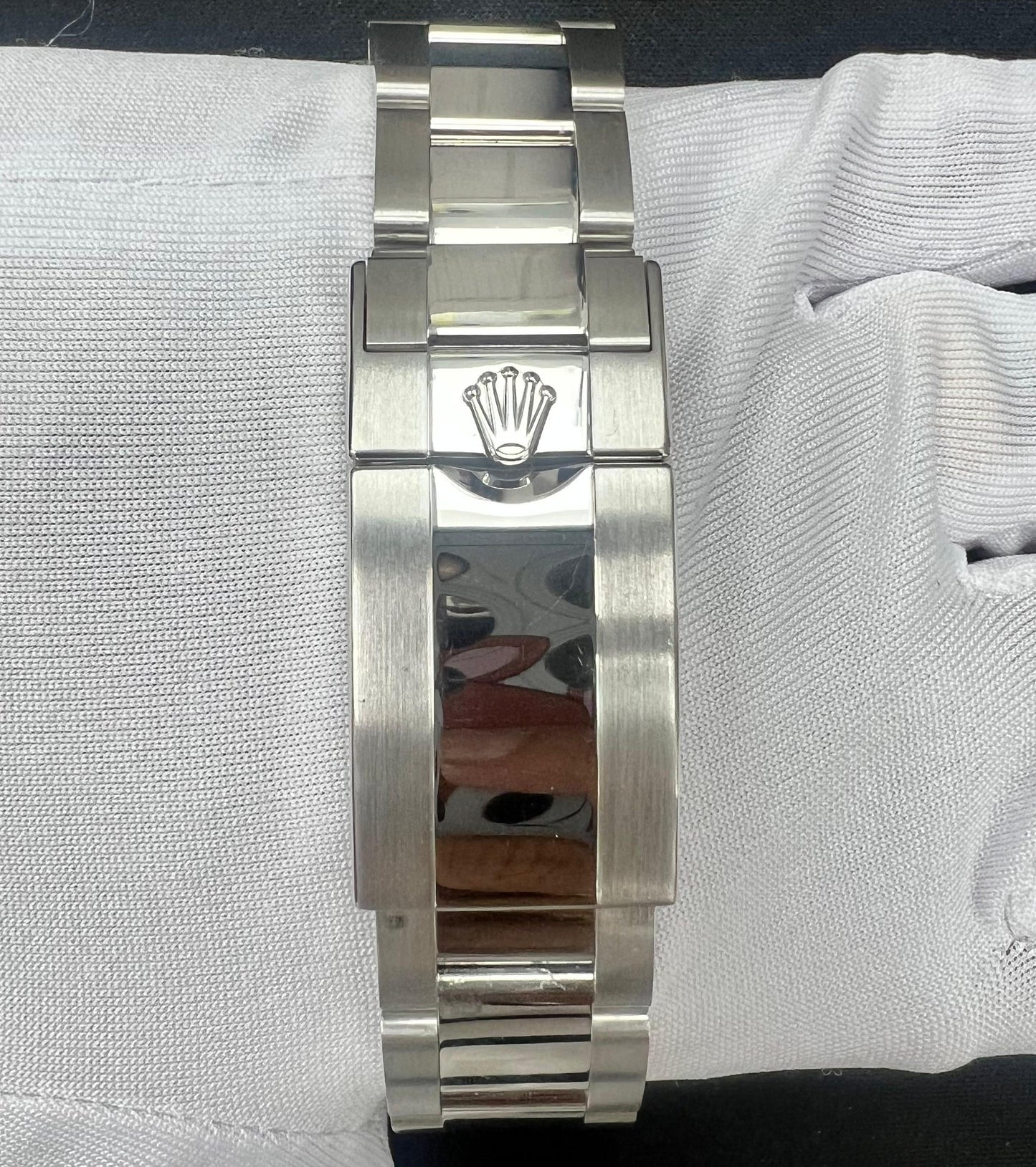 Platinum watch bracelet with Rolex logo on a white gloved hand