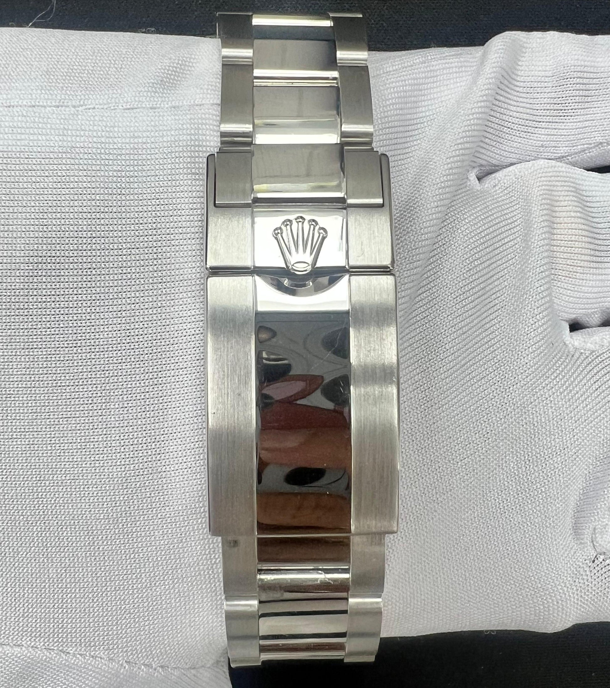 Platinum watch bracelet with Rolex logo on a white gloved hand